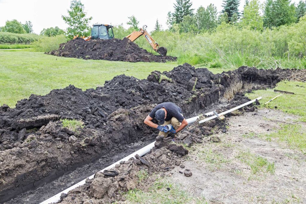 Understanding Septic Systems, Mound, septic installation outdoors in grassy area, backhoe and workers